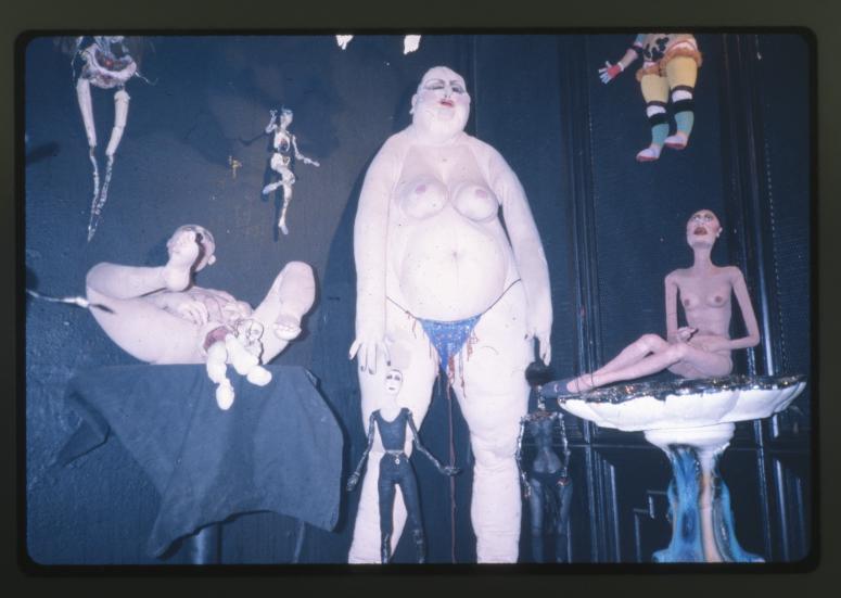 Alternate view lower end of the corner of dolls, several nude dolls, charred dolls, and clown sculpture, hermaphrodite doll giving birth